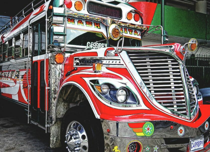 Muestra una vista de cerca de un viejo autobús escolar estadounidense que ha sido repintado en rojo brillante con mucho cromo, Cosas que hacer en Antigua Guatemala