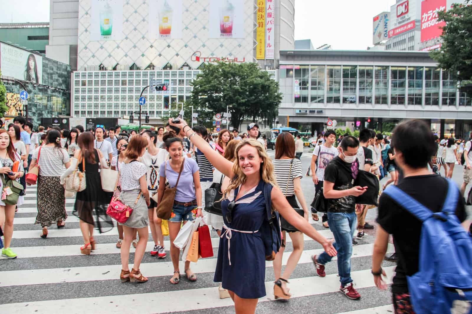 Una mujer con los brazos extendidos en el famoso cruce de Shibuya en la capital de Japón, Tokio. 