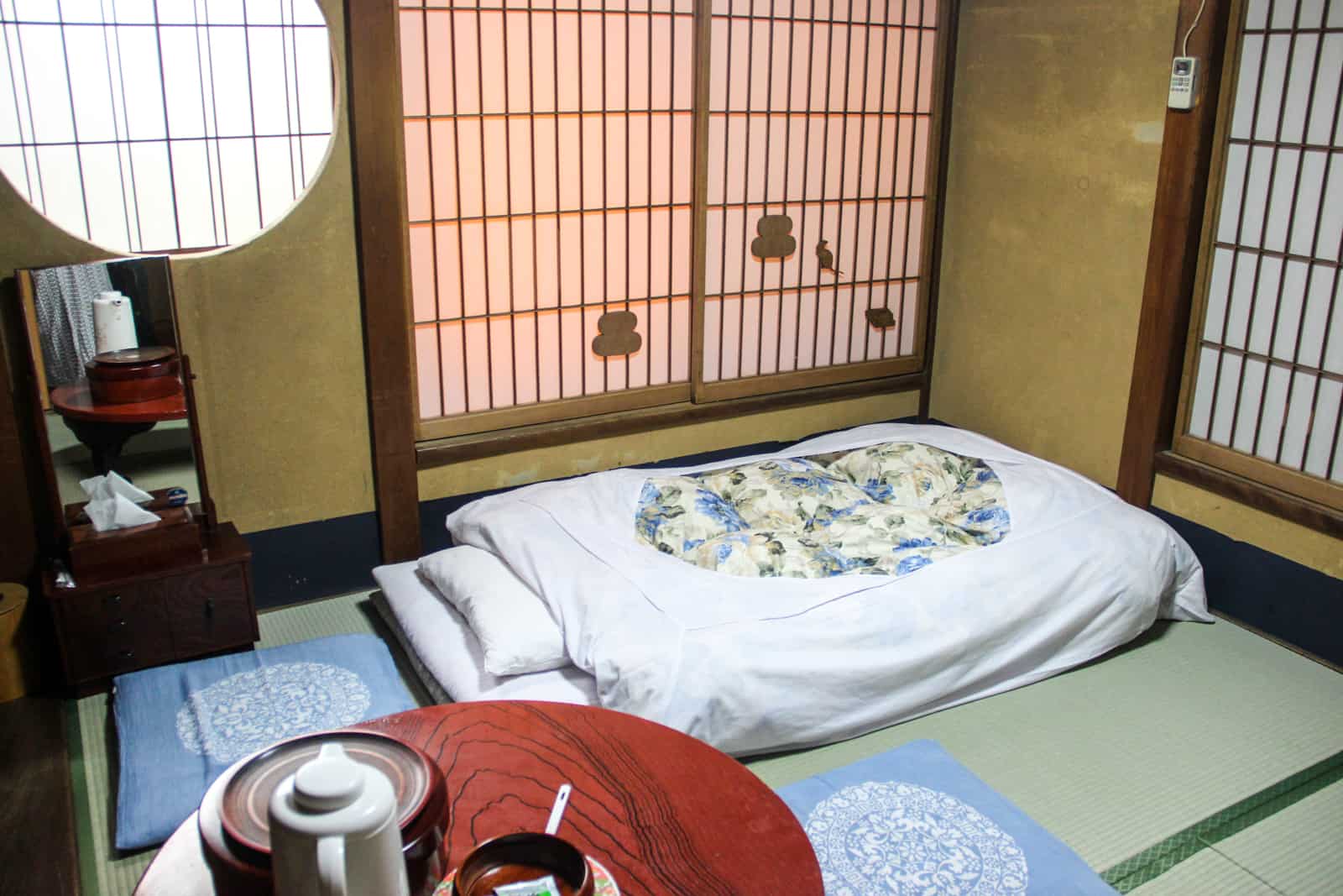 Alojamiento tradicional japonés con ventanas cerradas, cama en el suelo y mesa de té, conocido como Ryoken.