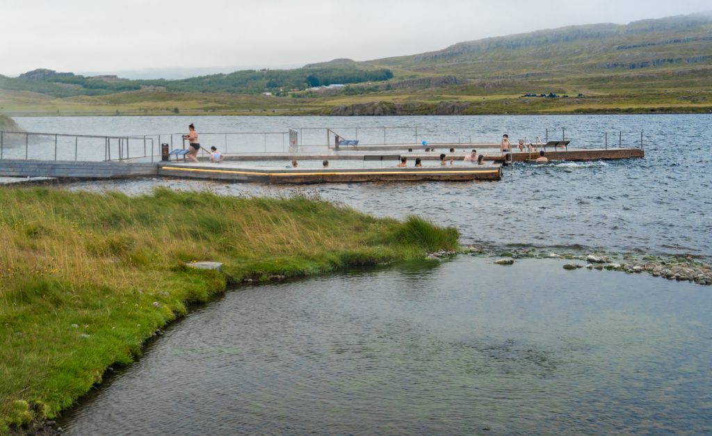 Dos piscinas flotantes en la distancia más allá de la orilla cubierta de hierba del lago.
