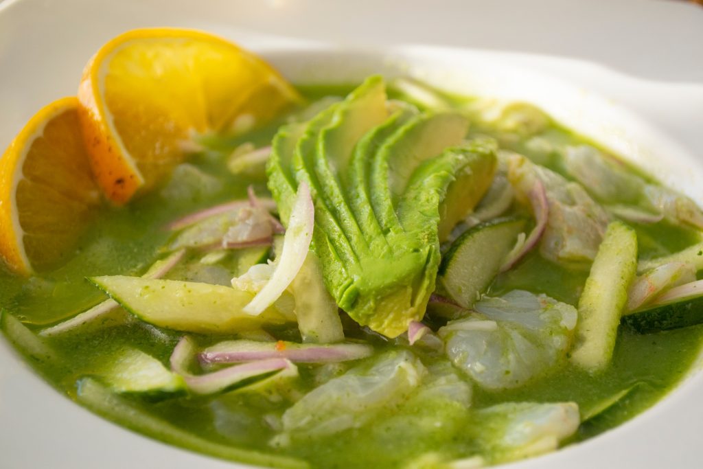Plato de aguachile de camarón, camarón marinado nadando en salsa verde con totopos y aguacate