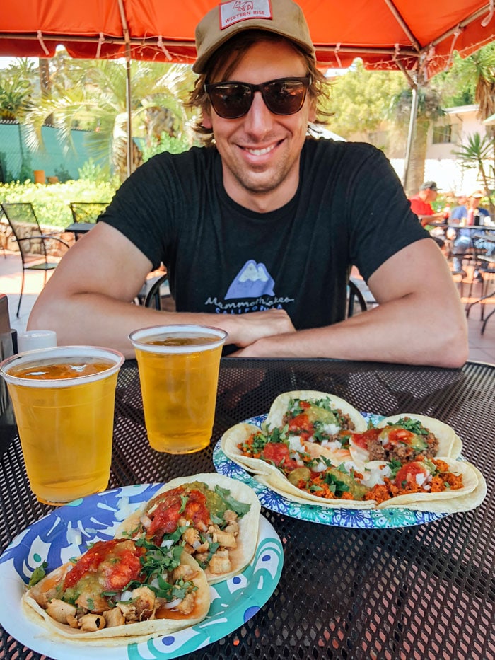 Hombre sonriente sentado frente a un plato de tacos