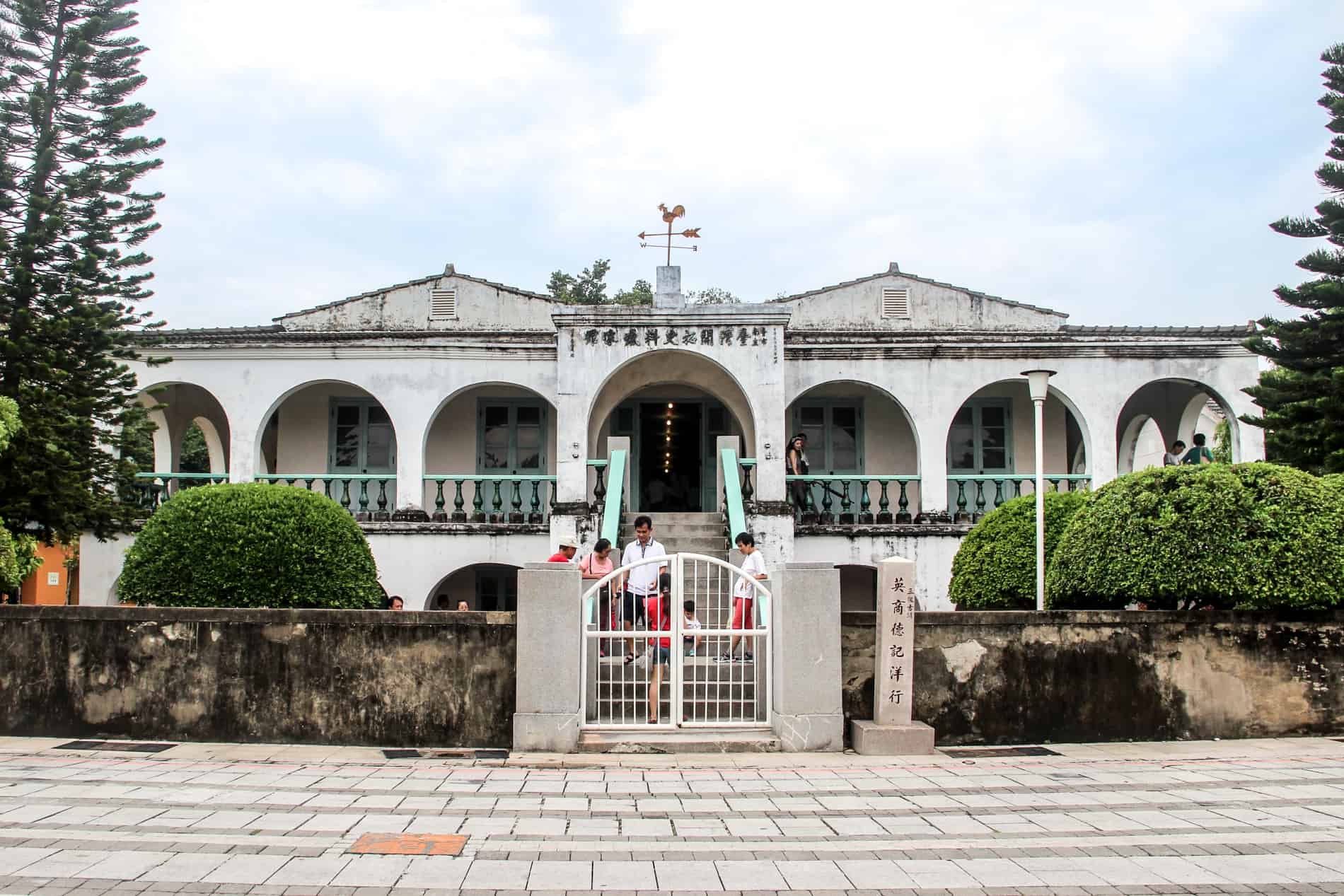 La gente en la escalera de un edificio de estilo colonial porticado blanco - la antigua Casa Mercantil Tait & Co en Tainan. 