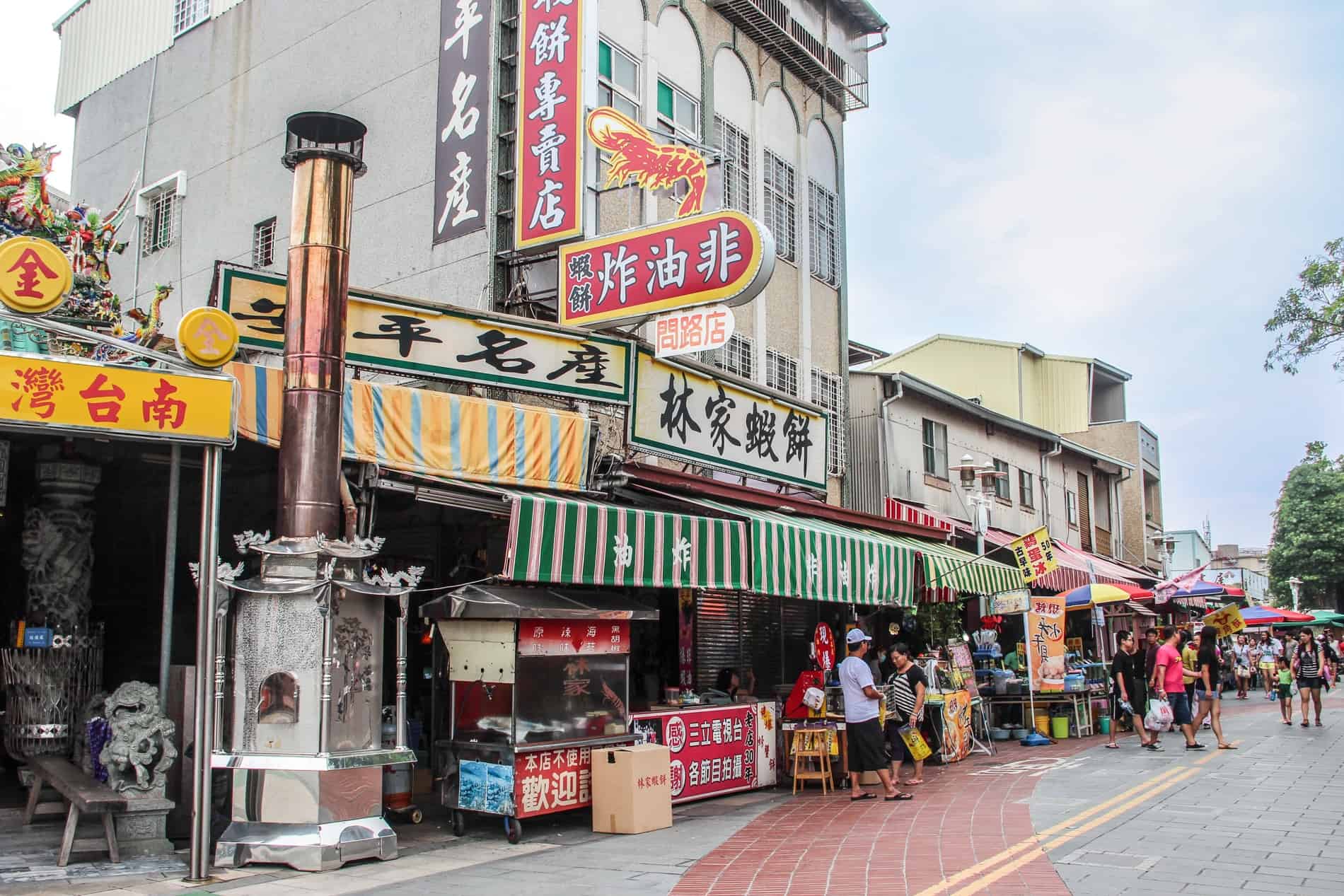 Gente en una calle llena de tiendas y vendedores ambulantes de comida en el centro de la ciudad de Tainan. 